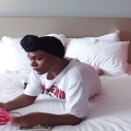 black woman with headwrap reading book in hotelroom